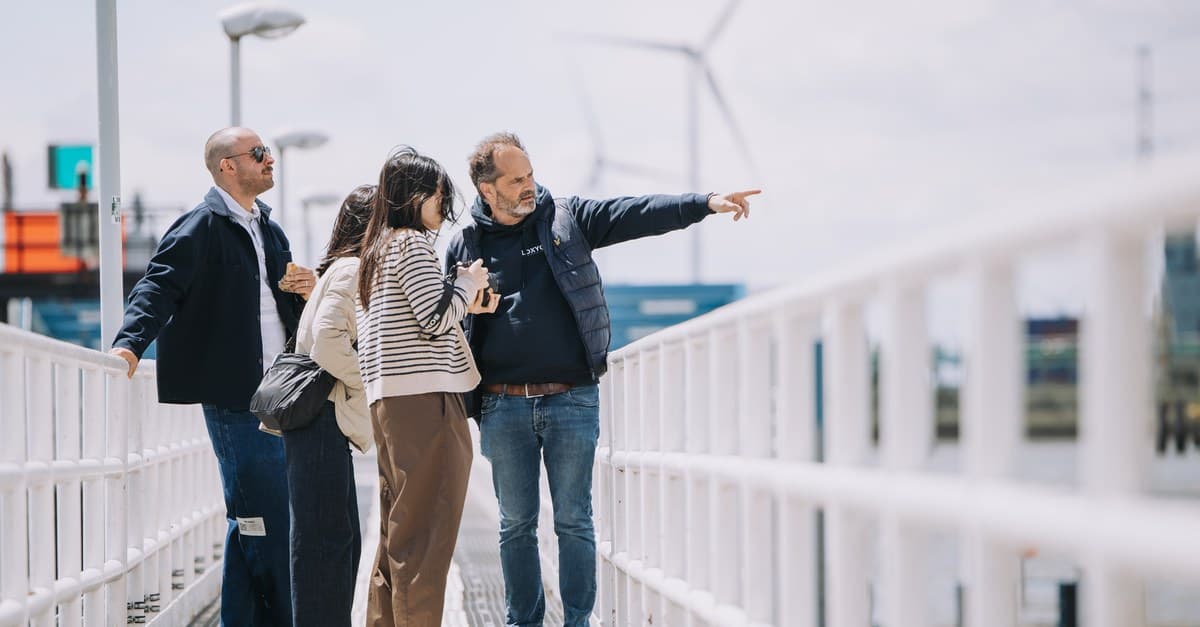 A Loxygen guide pointing out port infrastructure to a group on a dockside walkway